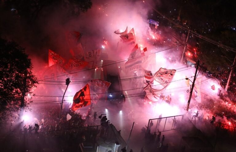 torcida do são paulo recebendo o elenco tricolor em frente ao portão principal com sinalizadores e bandeirões